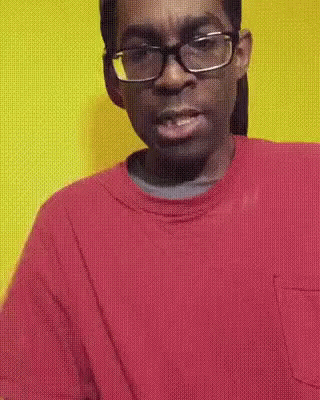 an african american man with a purple sweater and blue shirt and glasses