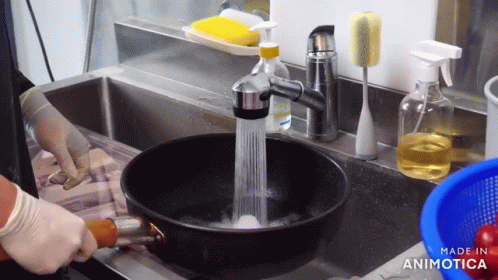 a person washing dishes in a sink while wearing gloves