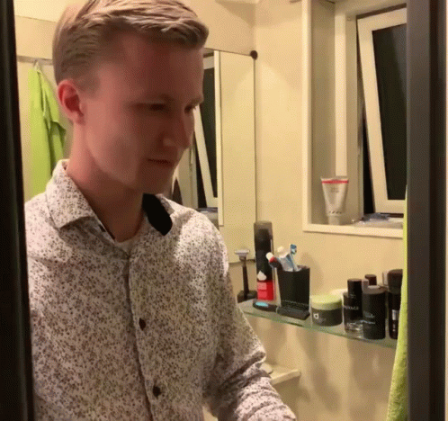 a young man looking at the mirror of his bathroom