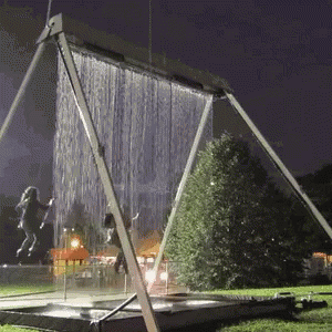 a sculpture with water pouring down it in a park