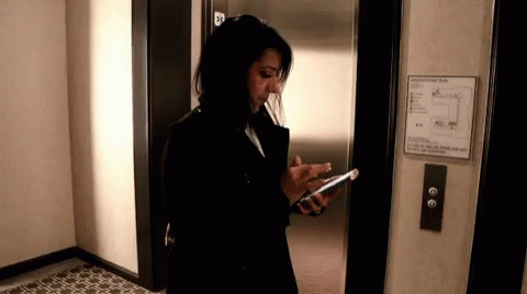 a woman in dark clothing standing outside of an elevator