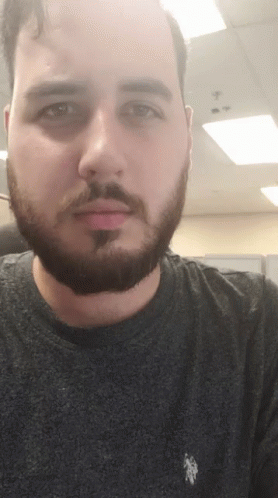man with beard staring at camera taking selfie