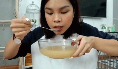 a young asian lady eating with a spoon and blue powder