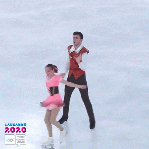 two skaters skate on a large skating rink