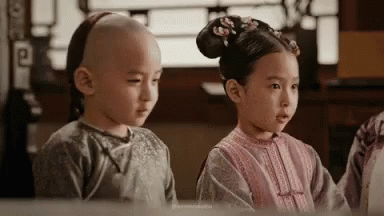 two children in traditional asian dress staring into a mirror