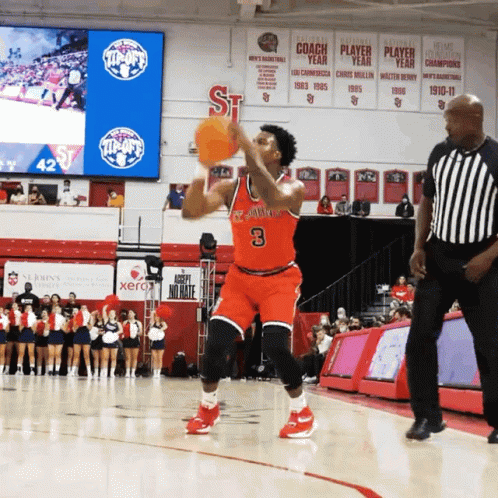 a man in blue uniform reaching to grab a basketball