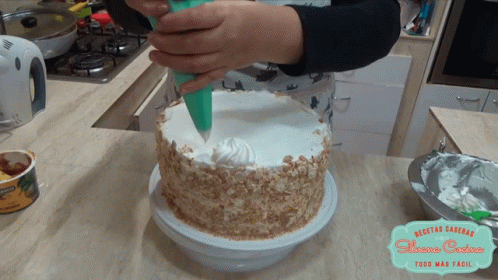 a person in gloves is frosting a cake