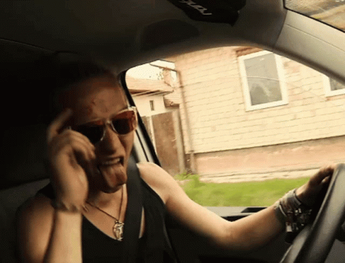 a man driving his car while talking on a phone