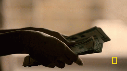 a person in gloves holding up a stack of money