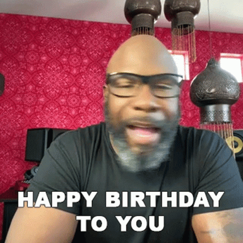 a person wearing glasses and making a face in the room with a sign saying happy birthday to you