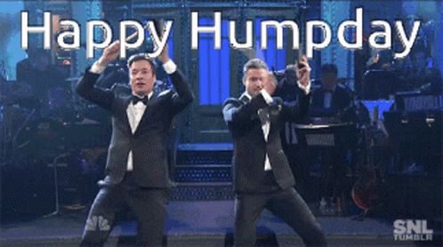 two men in suits dance with their hands in the air