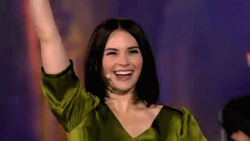 a woman wearing a green top waving at someone