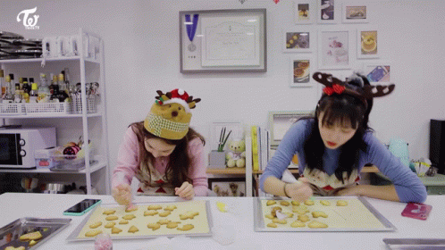 two girls sit at a table working on crafts