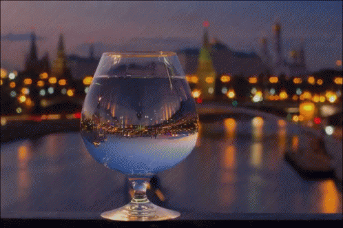 a large glass filled with white liquid sitting on a table next to a city