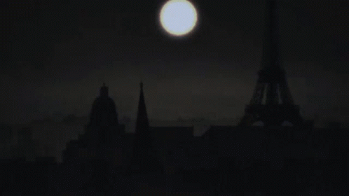 a full moon seen over a city with tall buildings