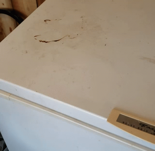 a dirty white refrigerator with a label on it