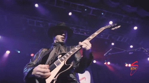 a man with a black hat is playing a guitar