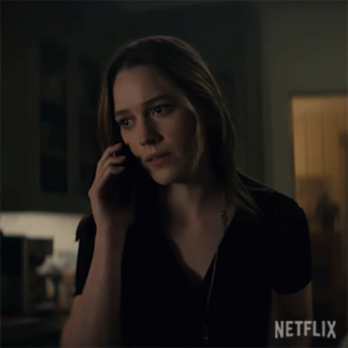 a woman in a darkened room talking on a phone