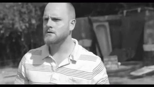 a bald man in striped shirt looking off into distance