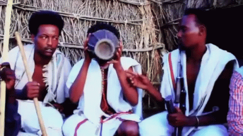 three men sitting next to each other, holding musical instruments