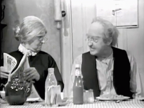 an old black and white po of an elderly man and woman reading the menu