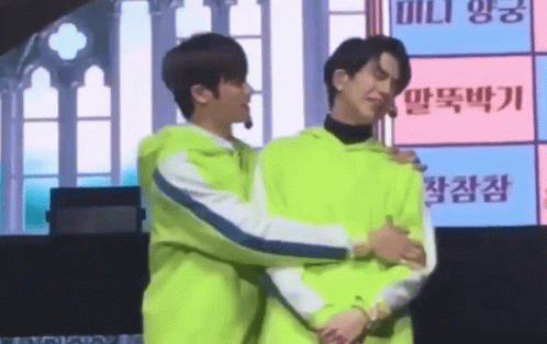 two men in matching outfits hugging each other on a stage