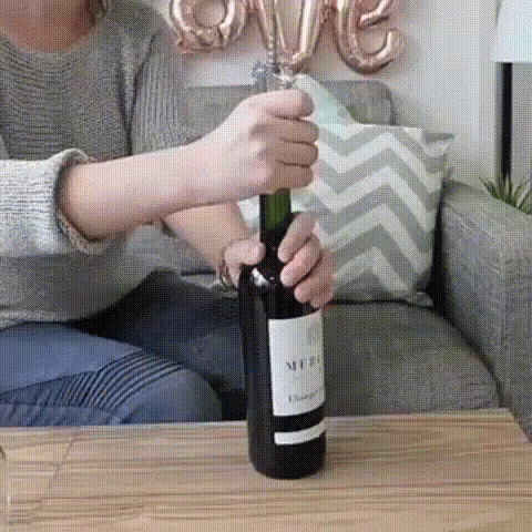 a woman opening a wine bottle on top of a table