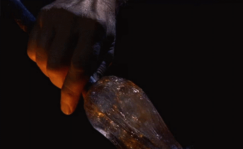 a blue glove holds a metal object on its tip