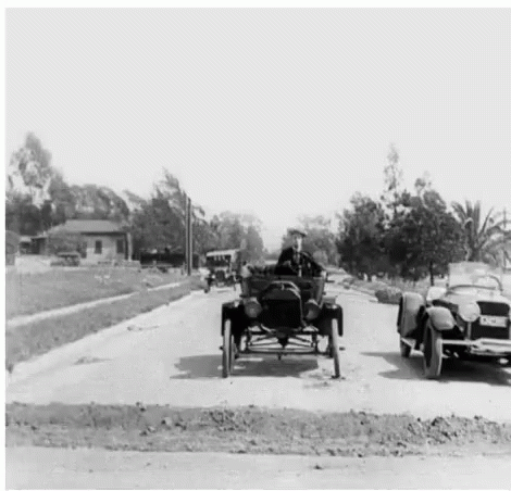an old time car pulling a side car down the road