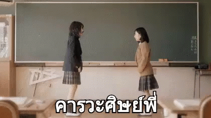 two girls in front of a blackboard with an asian writing message