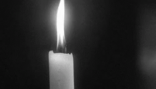 a lit candle burning on a table in the dark