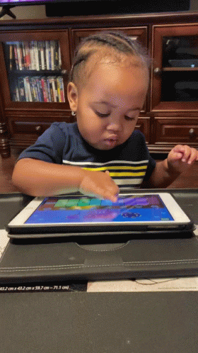 young child using tablet device on desk in school