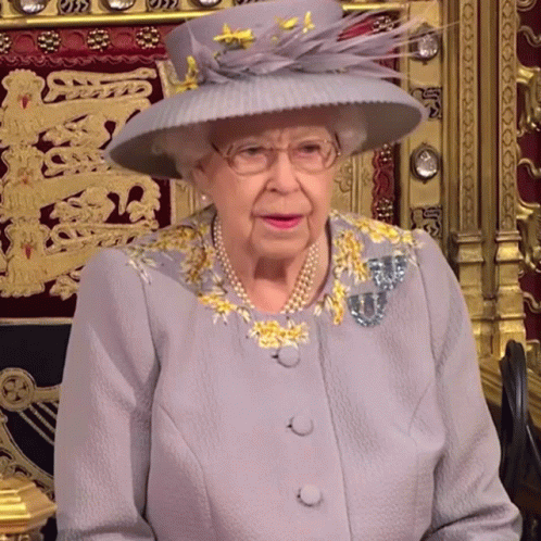 the queen of england sitting down and wearing a hat