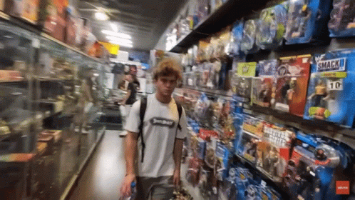 a young man in an aisle with many video game memorabilia