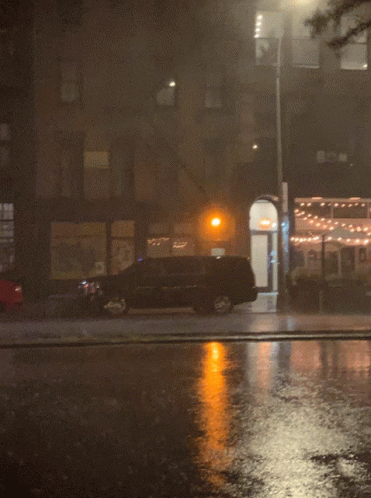 a rainy street is lit by lights in the dark