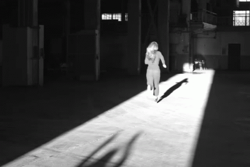 a woman walking in a building and casting a shadow