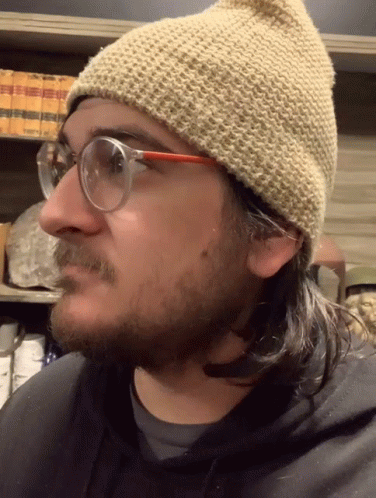 a man with glasses and a knitted hat is in the camera