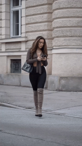 the woman is walking in the street using her cell phone