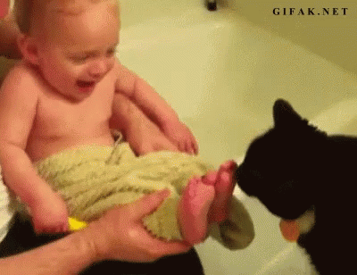 an infant and a cat playing with each other