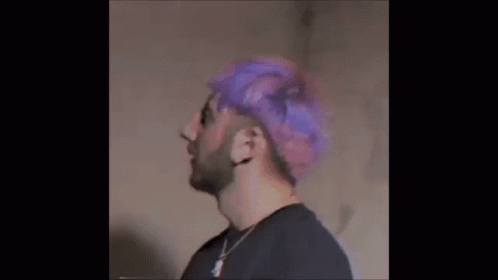 a man with bright pink wig and beard looks out over his shoulder