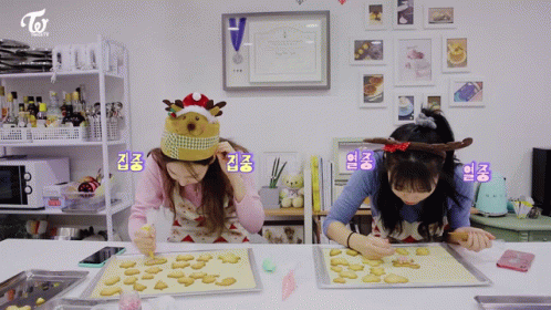two girls wearing hats while working on blue icing