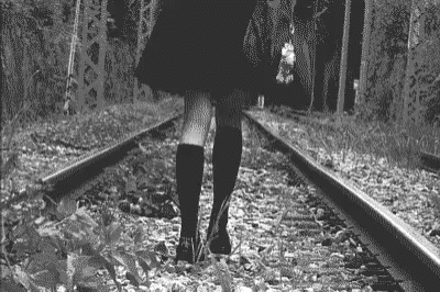 the woman is walking along train tracks carrying an umbrella