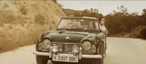an old car is driving down a mountain road