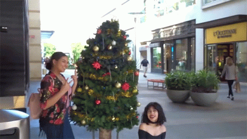a woman and child looking at a lit christmas tree