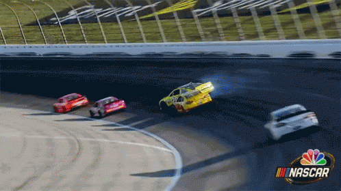 cars racing on a nascar track during the day