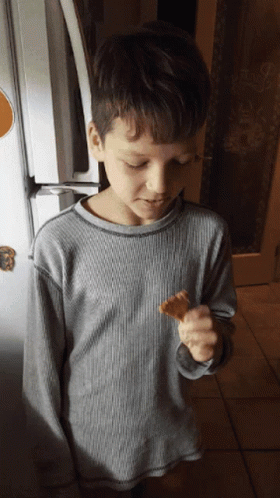 a boy with a tooth brush in his hand near an open refrigerator