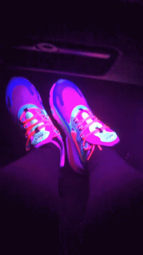 pink shoes with yellow laces and blue detailing on them in the dark