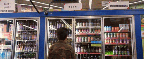 a person standing in front of a refrigerator filled with beverages