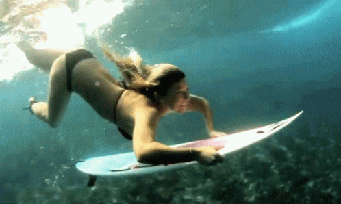 a woman in a bikini and wet suit surfing on her yellow surfboard
