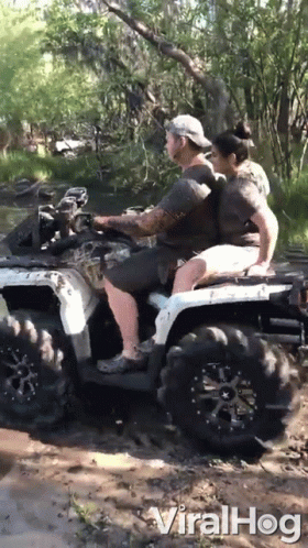 two people riding on the back of a quad in mud